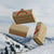 3 schwebende ANKERLIFT Holz-Geschenk-Verpackungen vor sonniger Winterlandschaft im Skigebiet