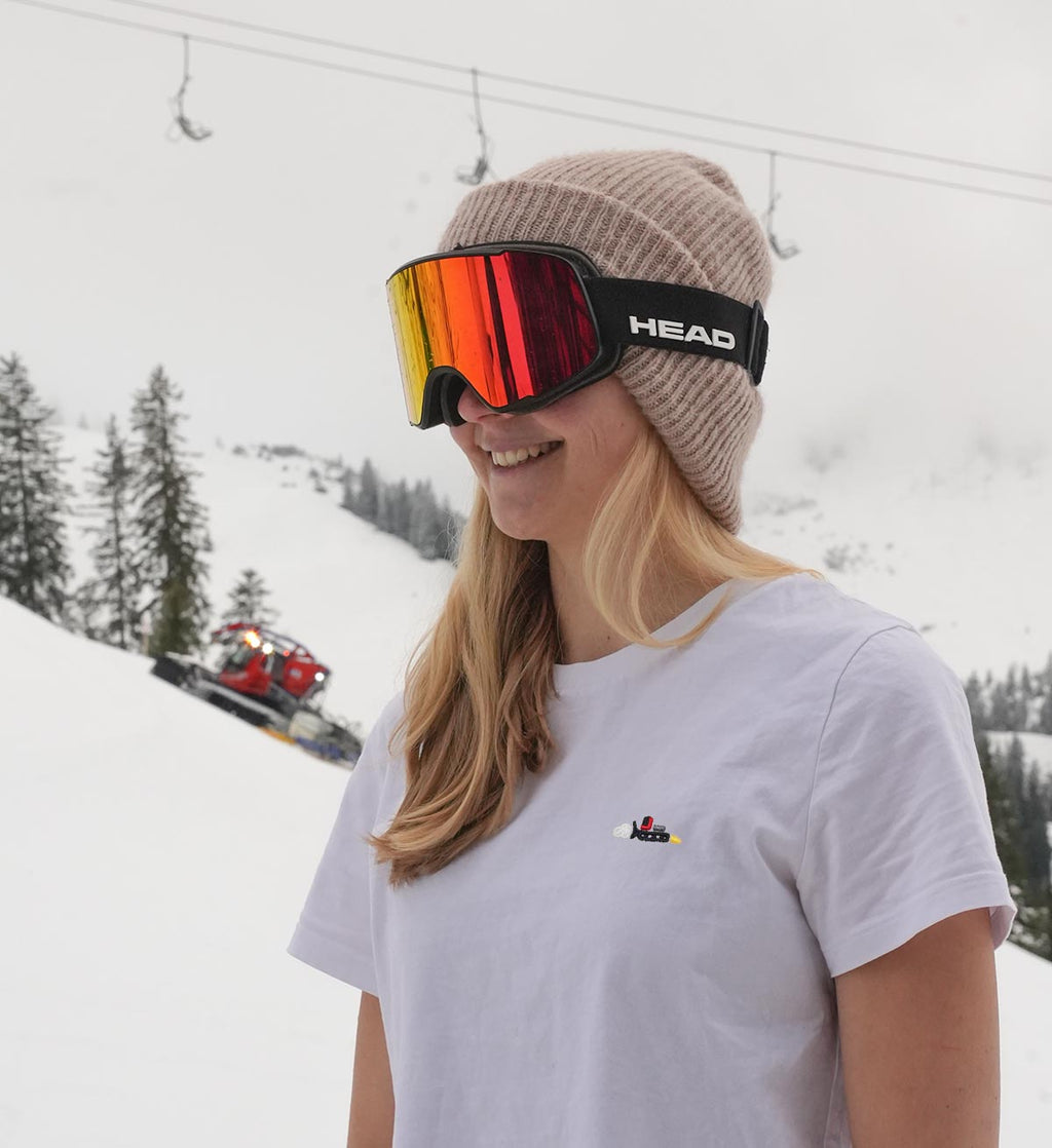 Skifahrerin trägt weißes Pistenraupen Stick Tshirt von Ankerlift im Skiurlaub