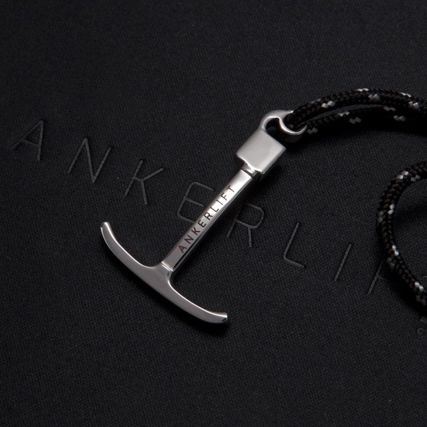 ANKERLIFT Armband für Wintersportler aus Edelstahl mit schwarzem Band auf schwarzem Hintergrund.
