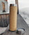 Isolierflasche aus Bambusholz steht auf einem Holzbrett, der Deckel liegt daneben.