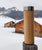 ANKERLIFT Thermoflasche aus Bambusholz vor einem idyllischen Blick auf Holzhütten und verschneiten Bergen