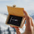 Offene Verpackung mit ANKERLIFT Armband in schwarz in den Händen gehalten vor Bergen im Winter
